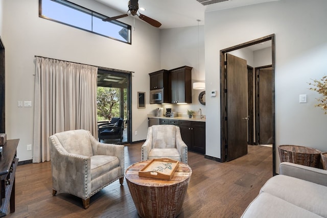 living room with dark hardwood / wood-style flooring, sink, ceiling fan, and a high ceiling