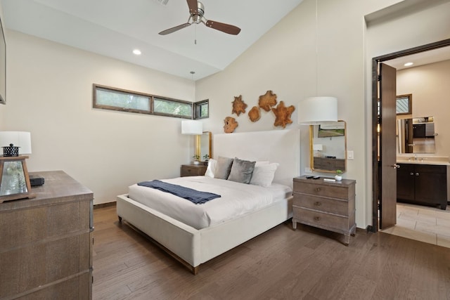 bedroom featuring recessed lighting, ensuite bathroom, vaulted ceiling, wood finished floors, and baseboards