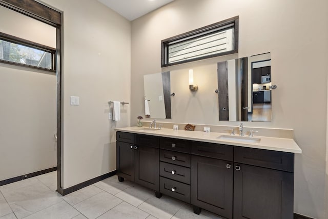 full bathroom with double vanity, baseboards, a sink, and tile patterned floors