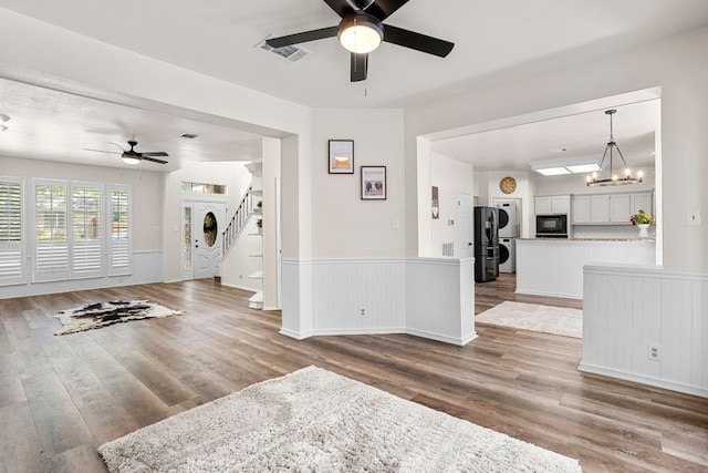 living room with ceiling fan with notable chandelier and light hardwood / wood-style flooring