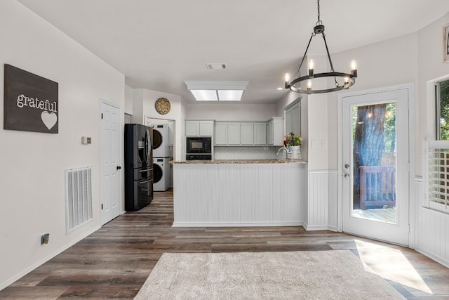 kitchen with stacked washing maching and dryer, dark hardwood / wood-style flooring, stainless steel refrigerator with ice dispenser, black microwave, and backsplash