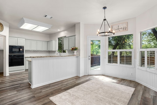 kitchen featuring black appliances, dark hardwood / wood-style flooring, kitchen peninsula, and plenty of natural light