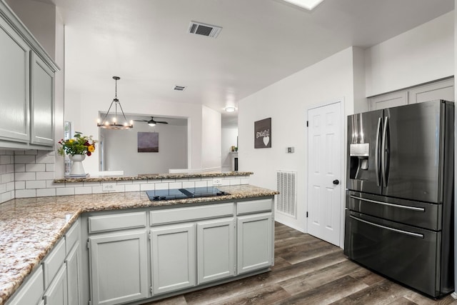 kitchen with kitchen peninsula, dark hardwood / wood-style flooring, light stone counters, decorative backsplash, and stainless steel refrigerator with ice dispenser