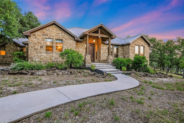 craftsman-style home with stone siding, a standing seam roof, metal roof, and fence