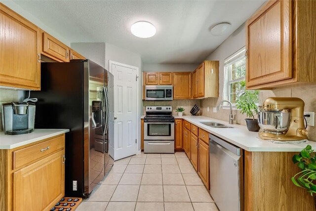 kitchen with light tile patterned floors, backsplash, appliances with stainless steel finishes, and sink