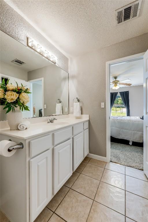 bathroom with ceiling fan, a textured ceiling, tile patterned floors, and vanity