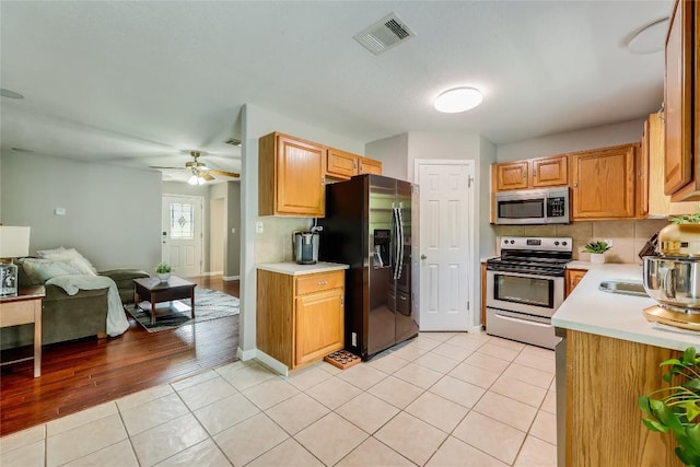 kitchen featuring ceiling fan, light tile patterned floors, stainless steel appliances, and tasteful backsplash