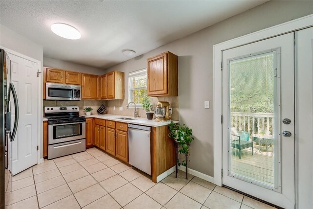 kitchen featuring stainless steel appliances, tasteful backsplash, light tile patterned flooring, a textured ceiling, and sink