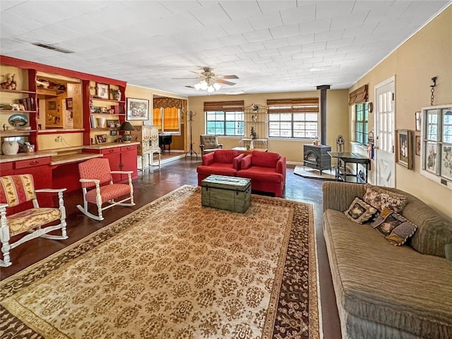 living room with dark hardwood / wood-style floors, ceiling fan, built in shelves, and a wood stove