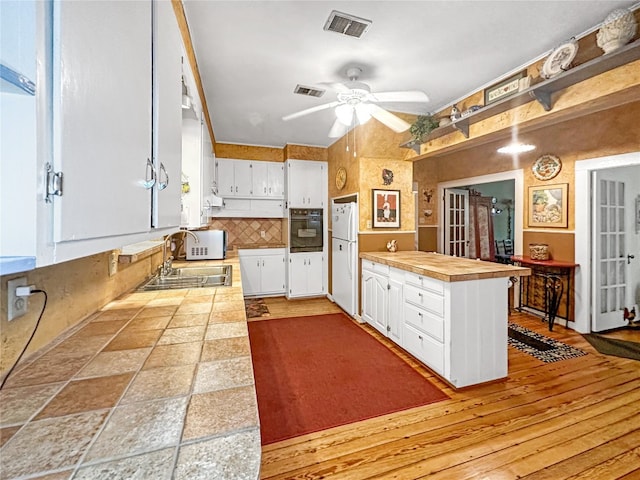 kitchen with white cabinetry, ceiling fan, white appliances, sink, and light hardwood / wood-style flooring