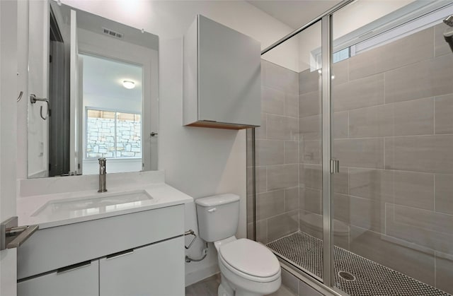bathroom with vanity, toilet, visible vents, and a stall shower