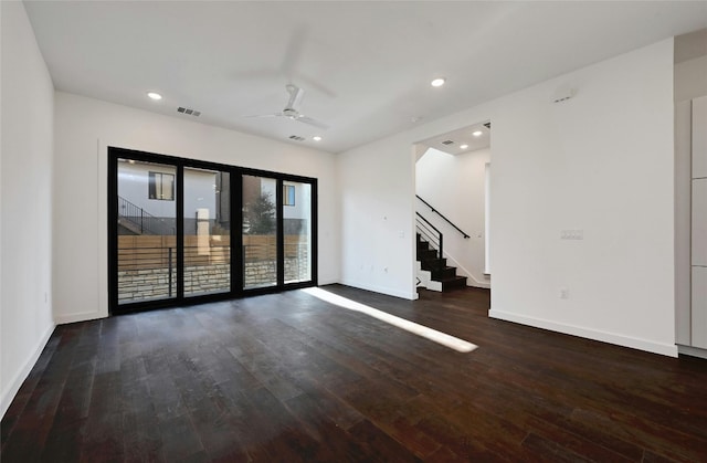 empty room with hardwood / wood-style flooring, a ceiling fan, baseboards, visible vents, and stairway