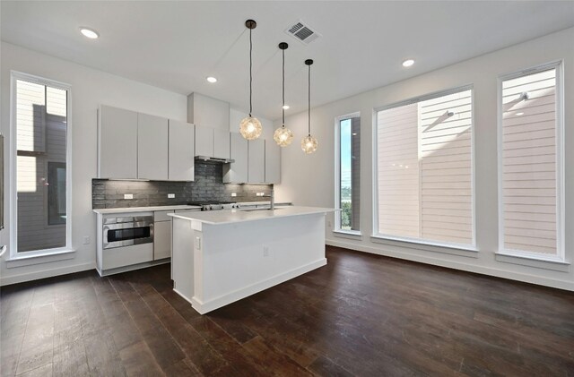 kitchen with light countertops, a wealth of natural light, dark wood finished floors, and oven