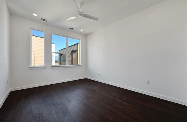 empty room with baseboards, ceiling fan, dark wood-style floors, and visible vents
