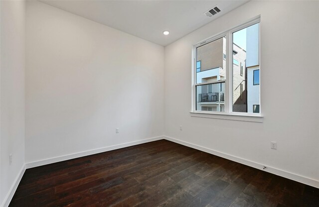 unfurnished room with dark wood-style flooring, baseboards, visible vents, and recessed lighting