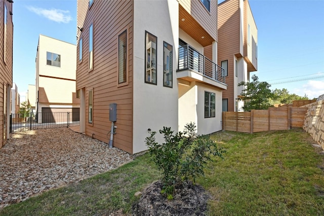 view of side of home featuring a balcony and a yard