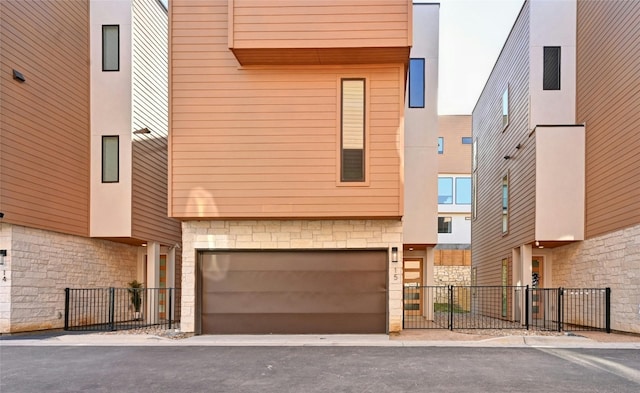 view of front of property with an attached garage, fence, stucco siding, and stone siding