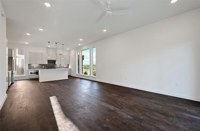 unfurnished living room featuring ceiling fan and dark hardwood / wood-style flooring