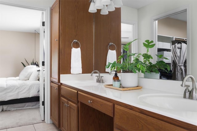 bathroom with ensuite bathroom, double vanity, tile patterned flooring, and a sink