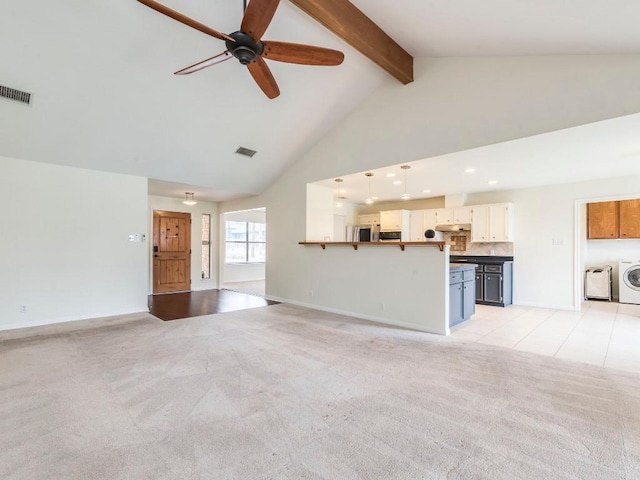 unfurnished living room with light carpet, visible vents, washer / clothes dryer, high vaulted ceiling, and beam ceiling