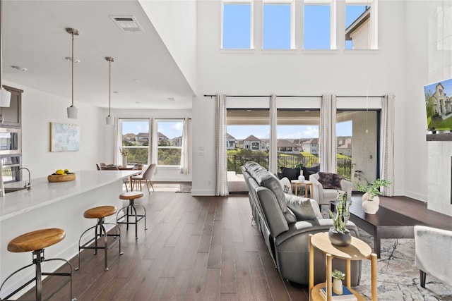 living room featuring sink, dark hardwood / wood-style flooring, and a towering ceiling