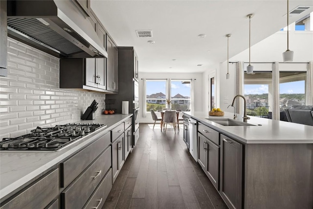 kitchen featuring wall chimney exhaust hood, sink, hanging light fixtures, dark hardwood / wood-style flooring, and stainless steel appliances