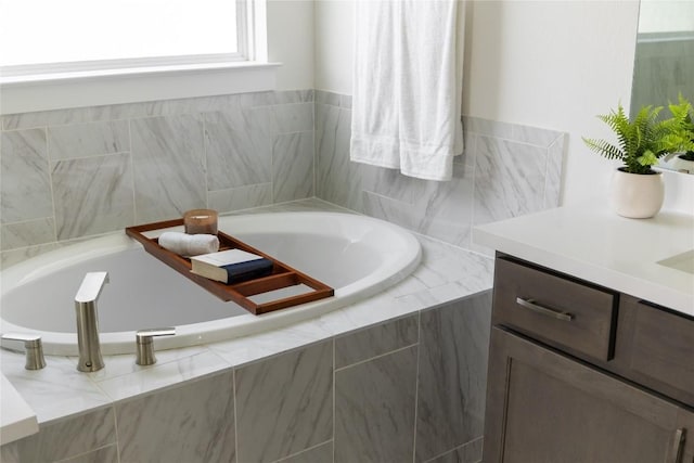 bathroom featuring vanity and tiled bath