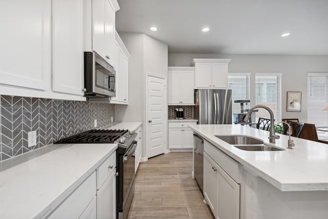 kitchen with tasteful backsplash, light hardwood / wood-style flooring, sink, white cabinets, and appliances with stainless steel finishes