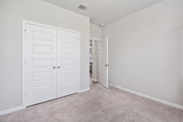 unfurnished bedroom with a closet and light colored carpet