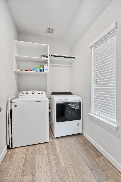 clothes washing area featuring independent washer and dryer and light hardwood / wood-style flooring