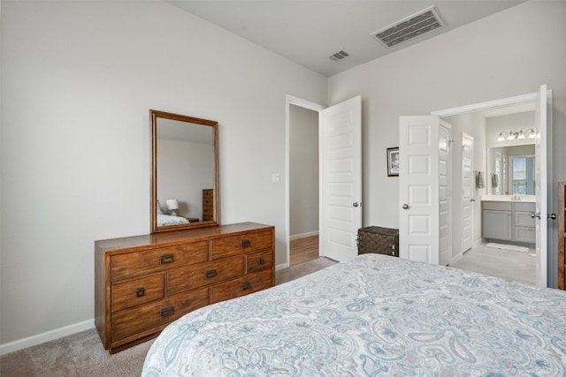 bedroom featuring light colored carpet and ensuite bath