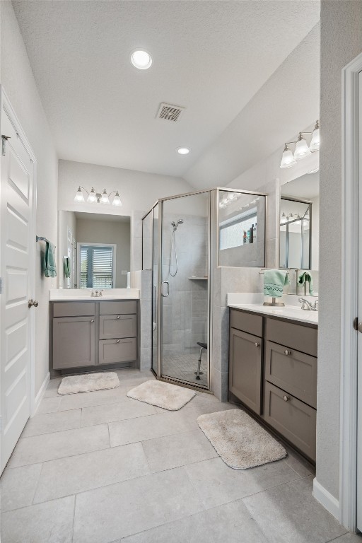 bathroom featuring vanity, a shower with shower door, tile patterned flooring, and a textured ceiling