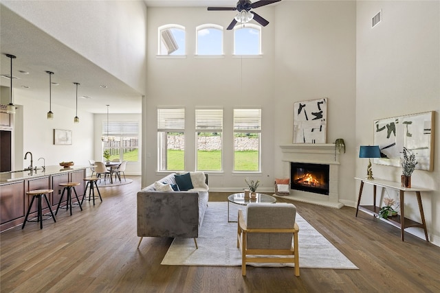 living room featuring sink, ceiling fan, dark hardwood / wood-style floors, and a high ceiling