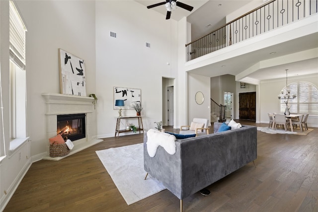 living room featuring a high ceiling, dark wood-type flooring, and ceiling fan with notable chandelier