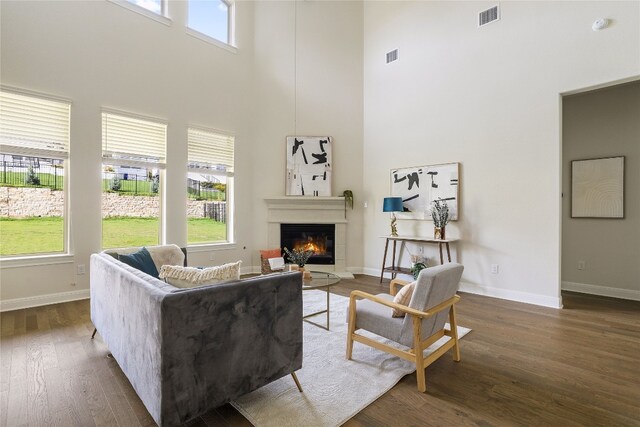 living room with dark hardwood / wood-style flooring and a towering ceiling