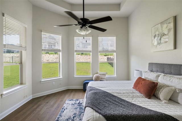 bedroom featuring multiple windows, ceiling fan, hardwood / wood-style floors, and a tray ceiling