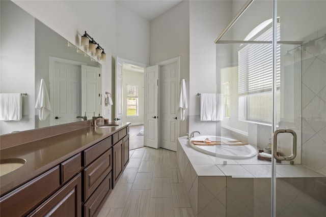 bathroom featuring plenty of natural light, separate shower and tub, tile patterned flooring, and double sink vanity