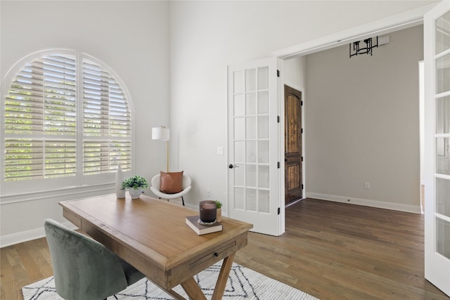 home office with a wealth of natural light, french doors, and dark wood-type flooring