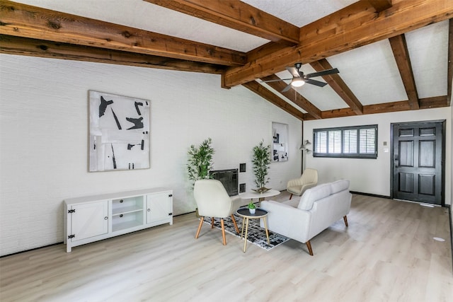 living area featuring light wood-type flooring, vaulted ceiling with beams, and ceiling fan