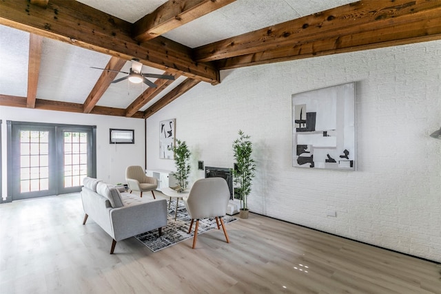 living room with light wood-type flooring, vaulted ceiling with beams, ceiling fan, and brick wall