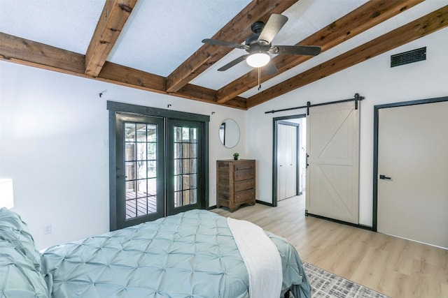 bedroom featuring ceiling fan, french doors, lofted ceiling with beams, a barn door, and light hardwood / wood-style floors