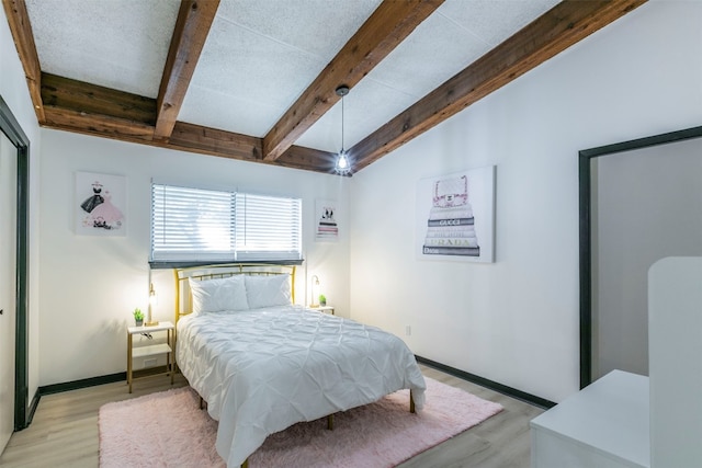 bedroom featuring light hardwood / wood-style flooring and lofted ceiling with beams