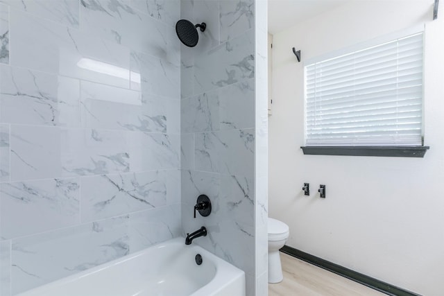 bathroom with hardwood / wood-style floors, toilet, and tiled shower / bath