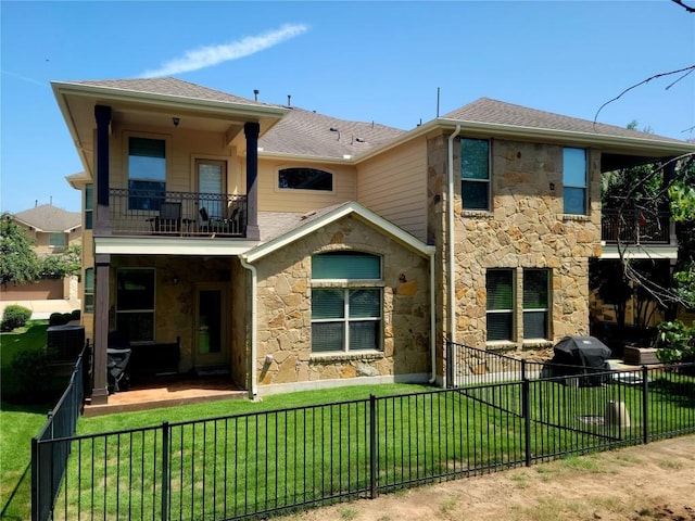 rear view of house with a balcony, a patio, and a lawn