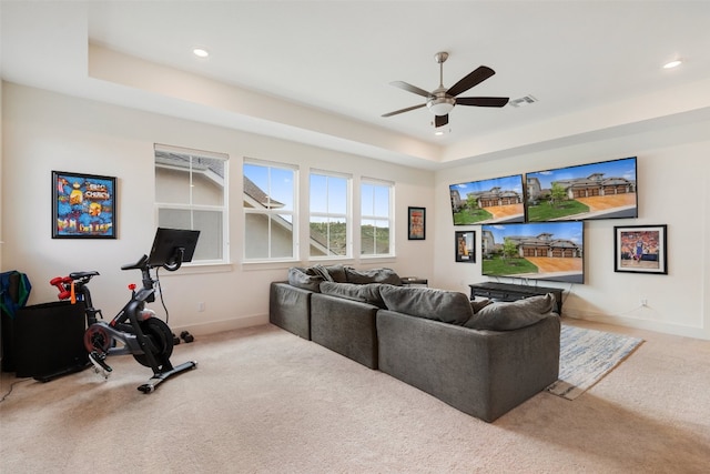 living room with light colored carpet, ceiling fan, and a tray ceiling