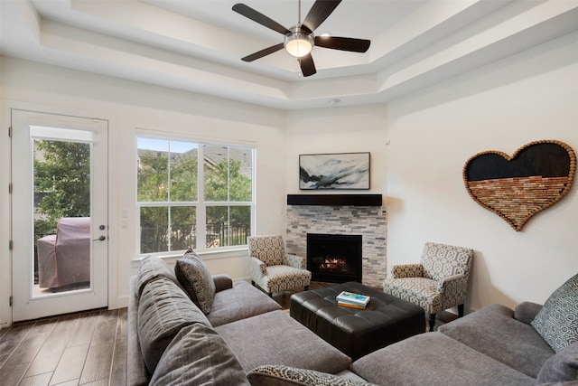 living room featuring a raised ceiling, ceiling fan, a fireplace, and hardwood / wood-style flooring