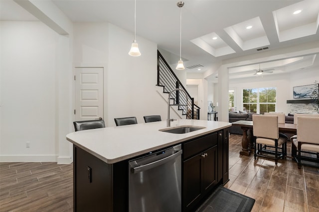 kitchen with ceiling fan, stainless steel dishwasher, dark hardwood / wood-style floors, decorative light fixtures, and a kitchen island with sink