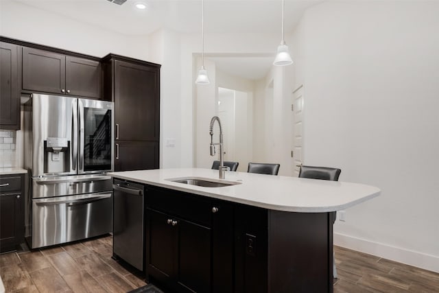 kitchen with sink, pendant lighting, a breakfast bar area, a kitchen island with sink, and appliances with stainless steel finishes