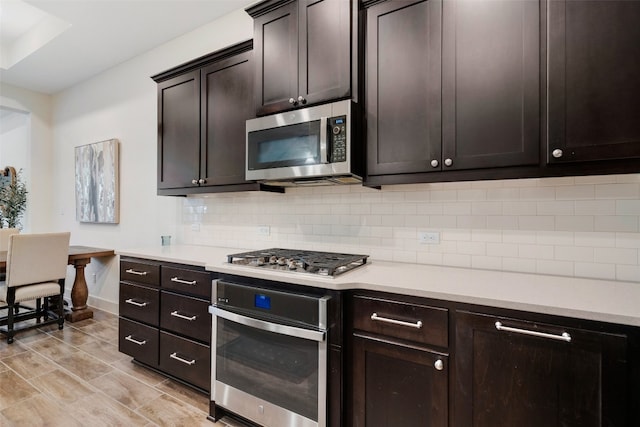 kitchen featuring dark brown cabinets, light hardwood / wood-style floors, decorative backsplash, and stainless steel appliances