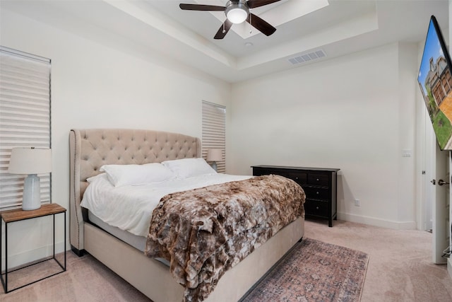 bedroom featuring ceiling fan, carpet floors, and a tray ceiling